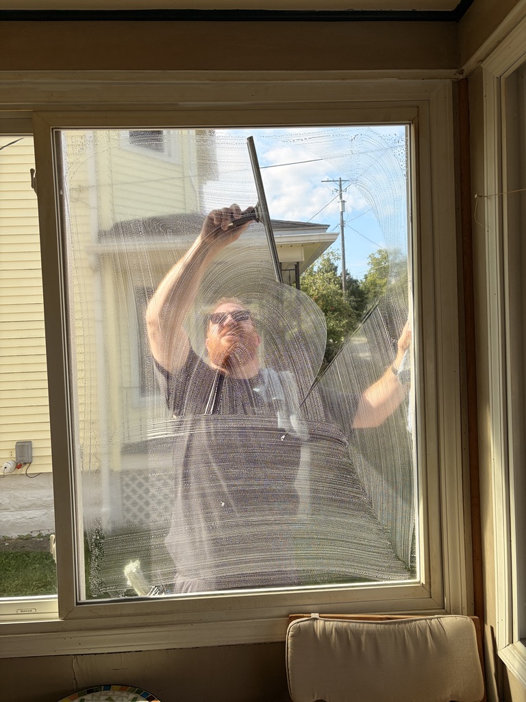 A Westlake Window Cleaners technician squeegeeing soapy glass, seen from inside the home