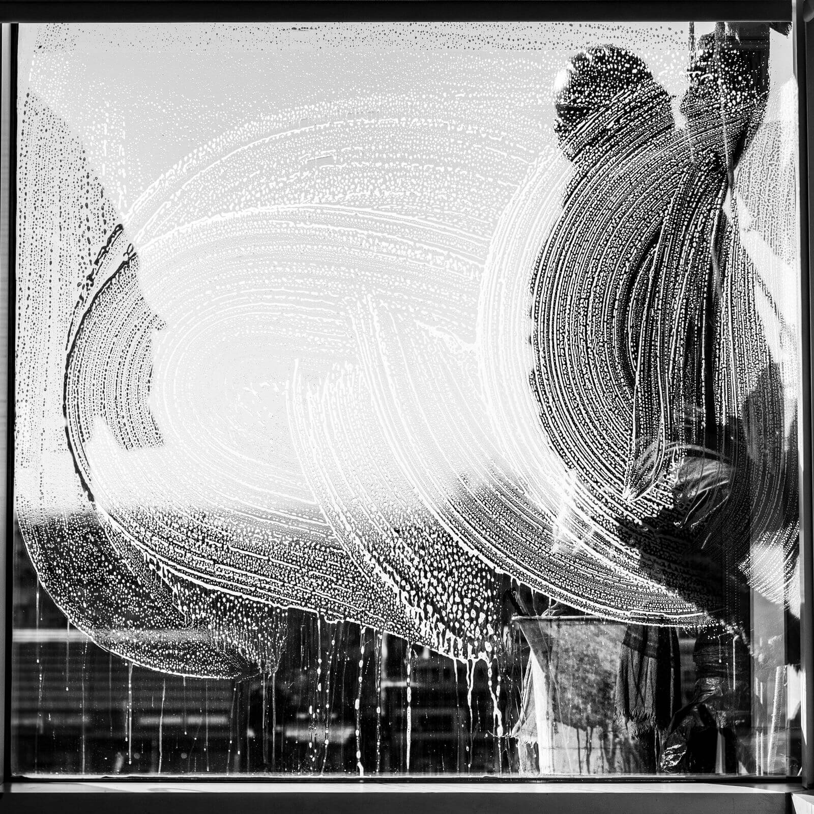 A window cleaner washing a sudsy window, seen from inside the home